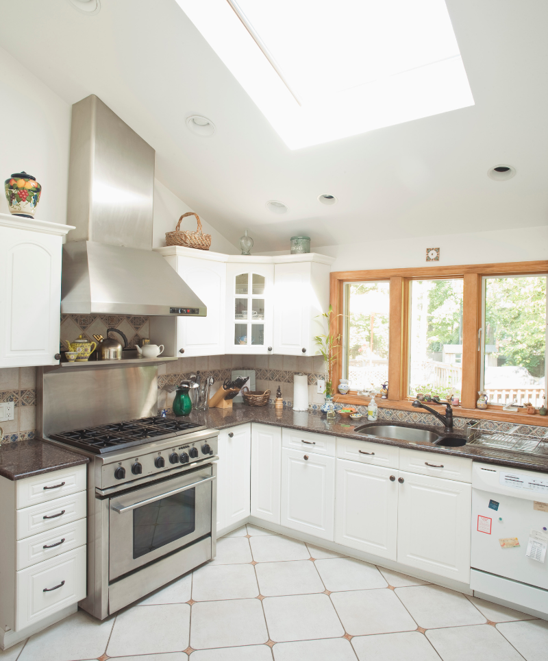 White kitchen with stainless range, skylight and corner windows